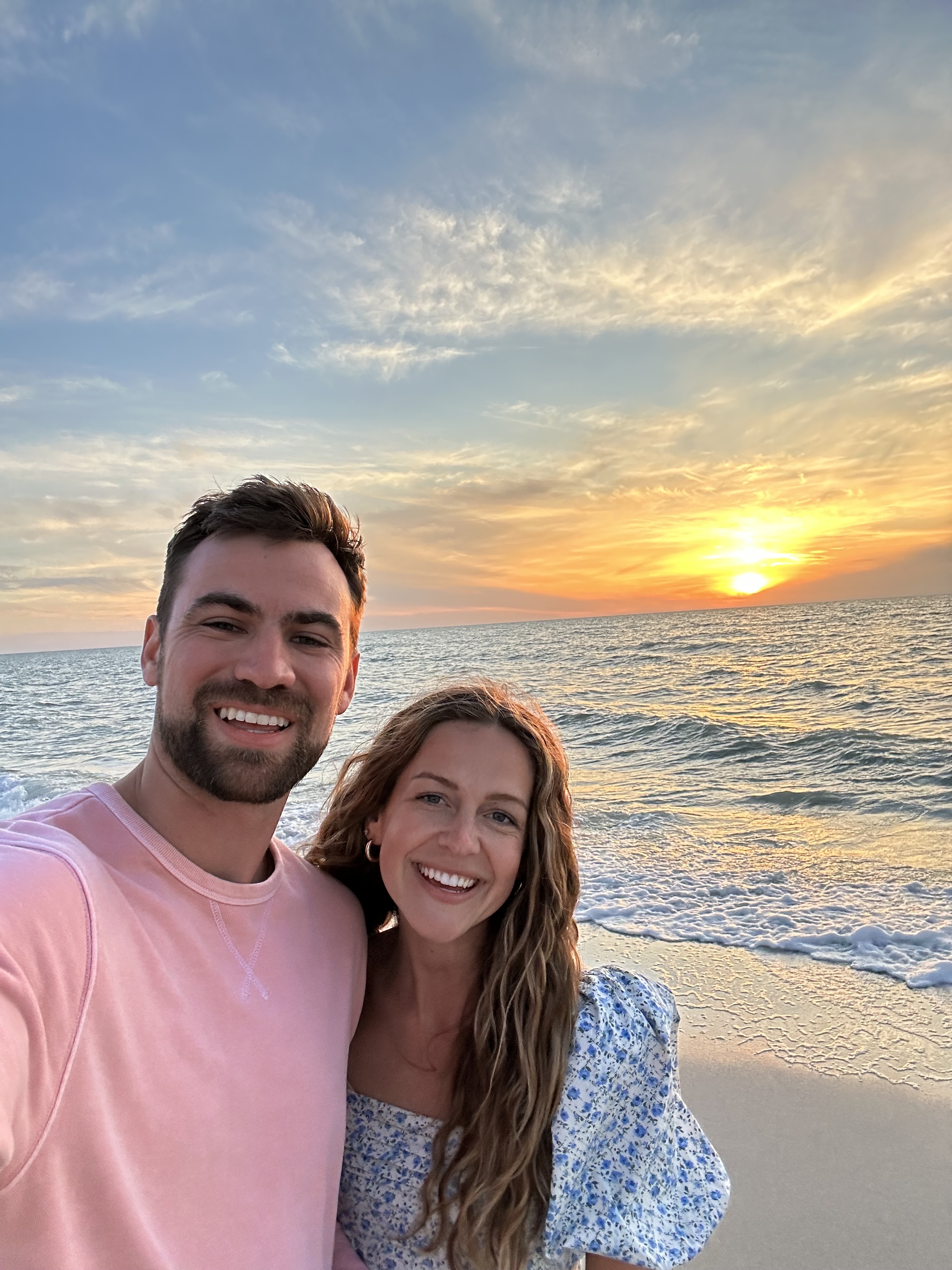 Luke Warner and his wife smiling at the beach at sunset.