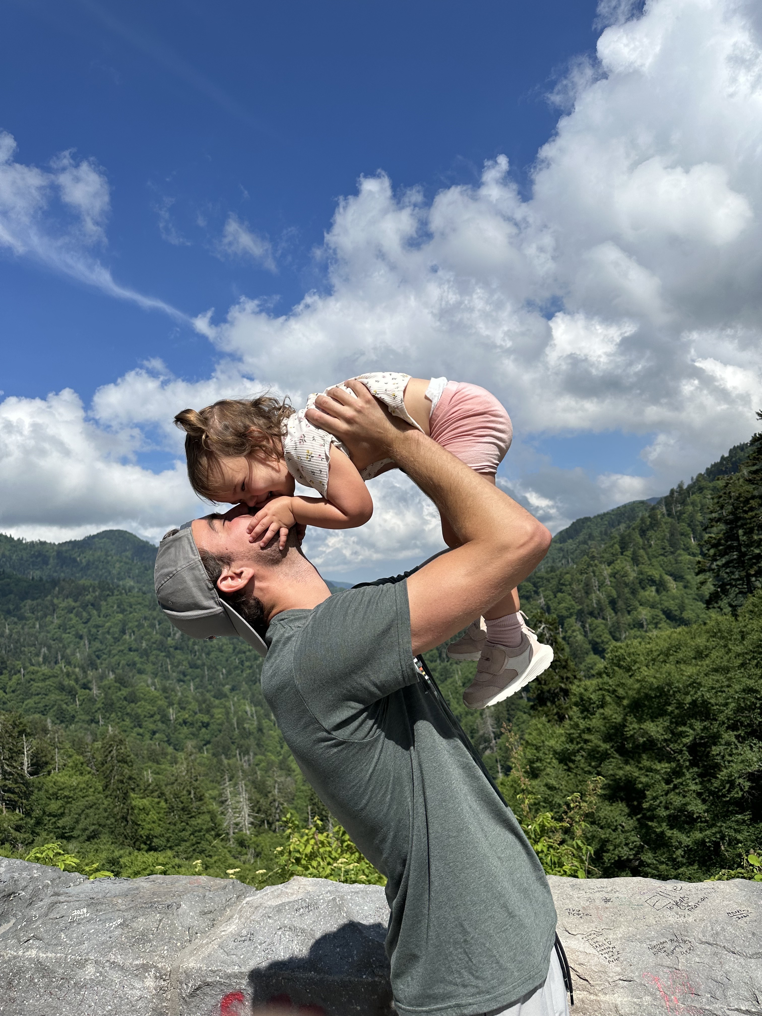 Luke Warner lifting his daughter in the mountains.